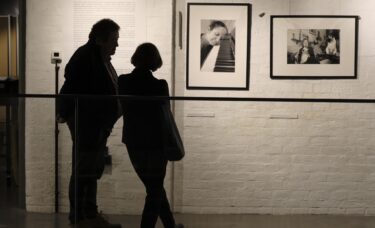 Dwie osoby stojące przy fotografiach z wystawy