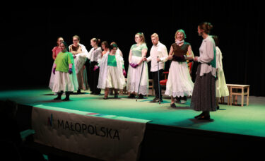 Tłum aktorów podczas sceny z katarynką