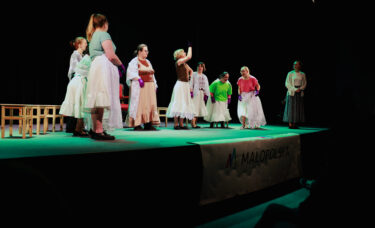 Scena spotkania towarzyskiego. Aktorzy w różnych pozach grają