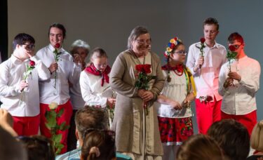 Autorka tekstów użytych w przedstawieniu, Pani Ewa Stadtmuller, z kwiatami, na tle grupu